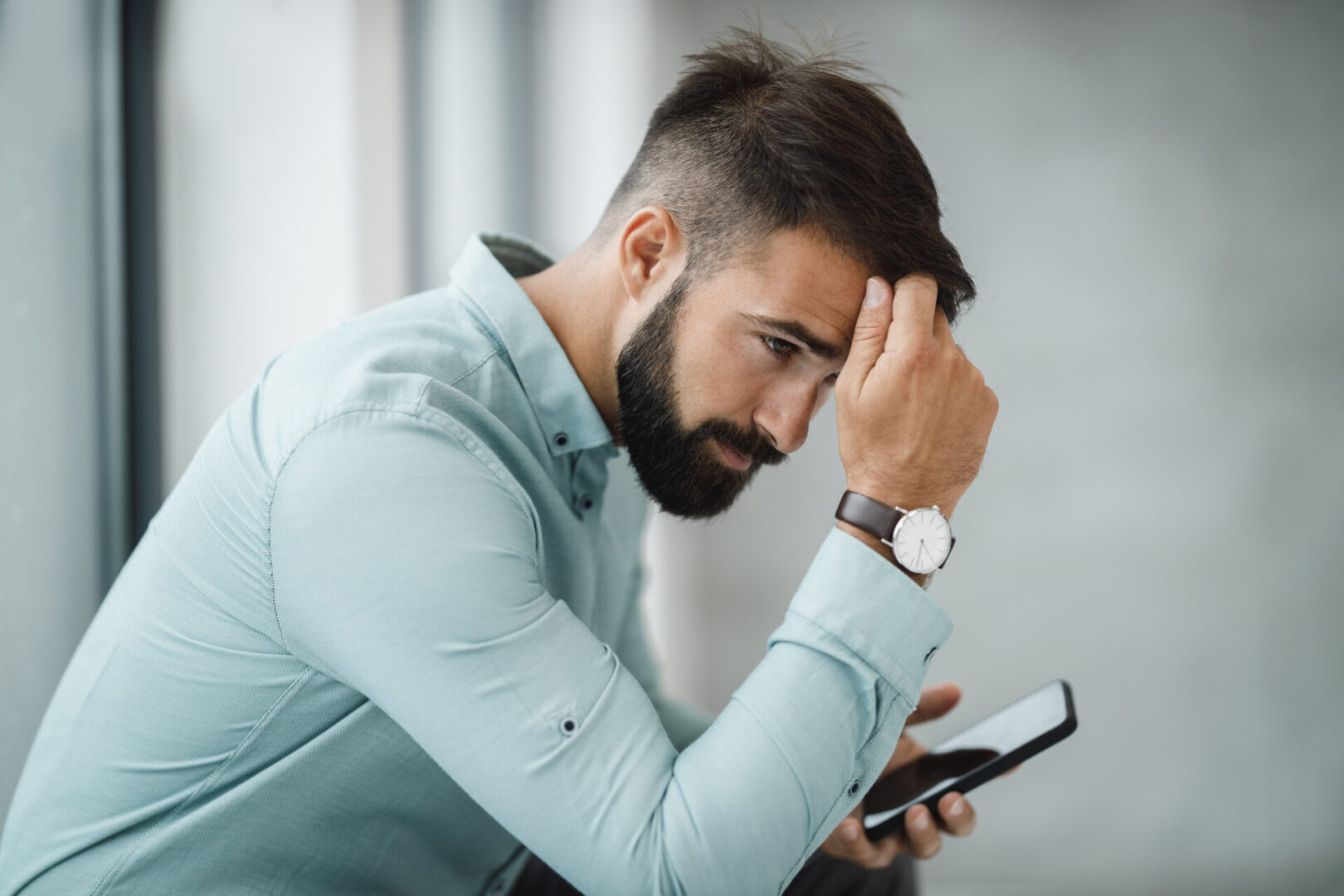 Man looking stressed while looking at phone. Get help for compulsive sexual behavior today.