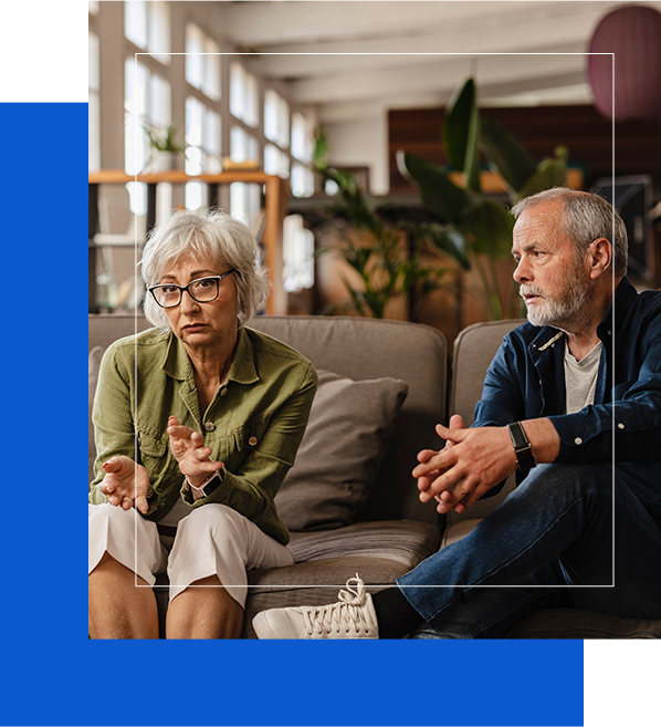 An elderly couple sitting on a sofa in a modern, warmly lit office, engaged in a thoughtful discussion, symbolizing relationship counseling services in Washington.